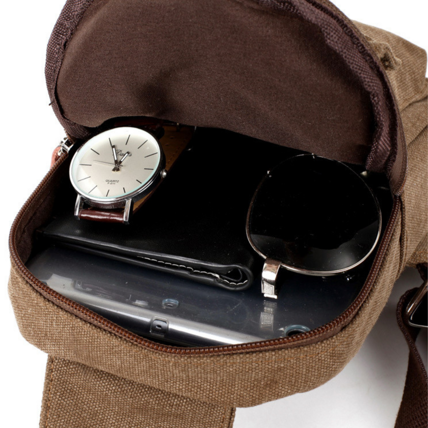 Interior of a canvas messenger sling bag showing a wrist watch, sunglasses, and a smartphone in brown color.