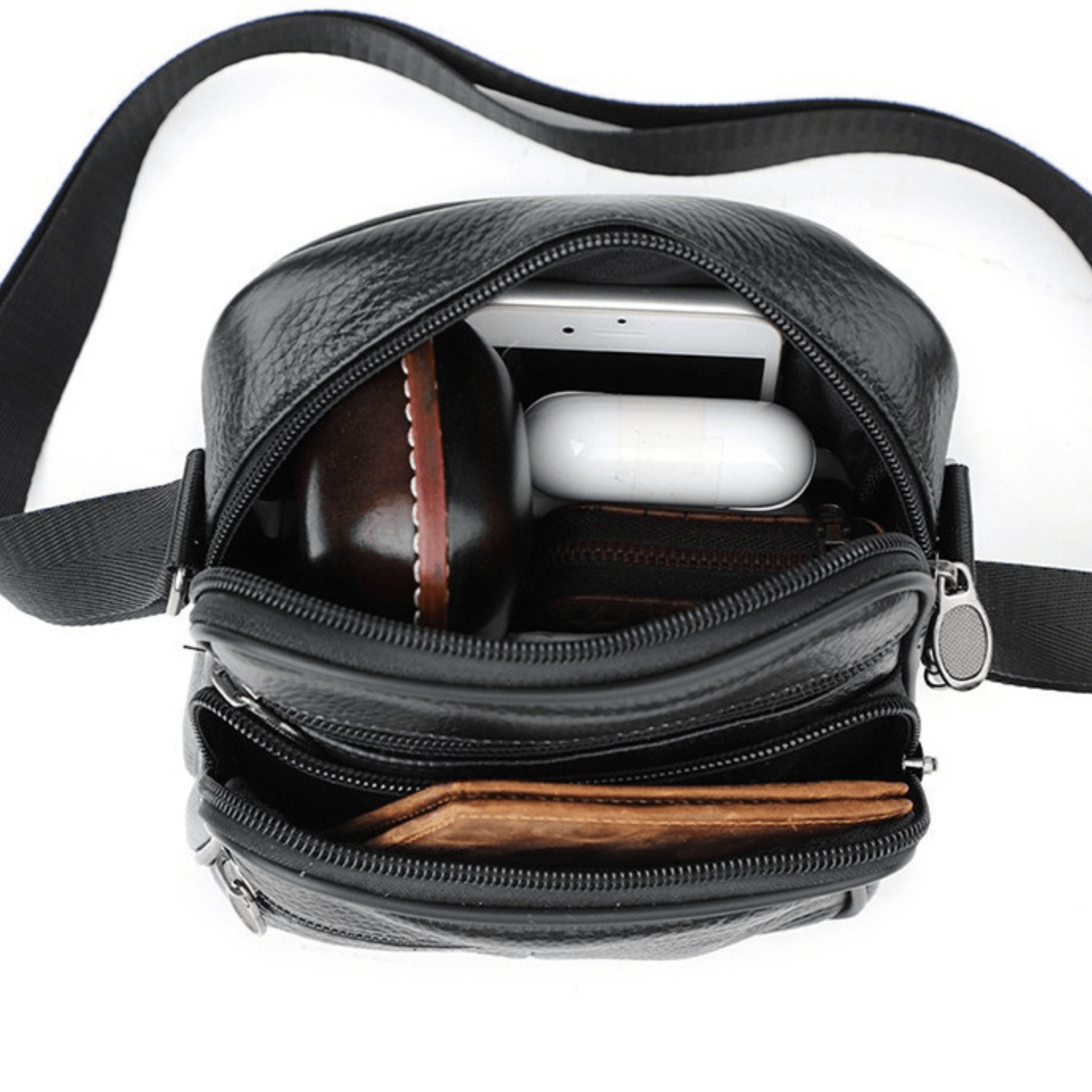 Interior view of a leather cross body bag showing multiple compartments and stored items like phone and wallet.