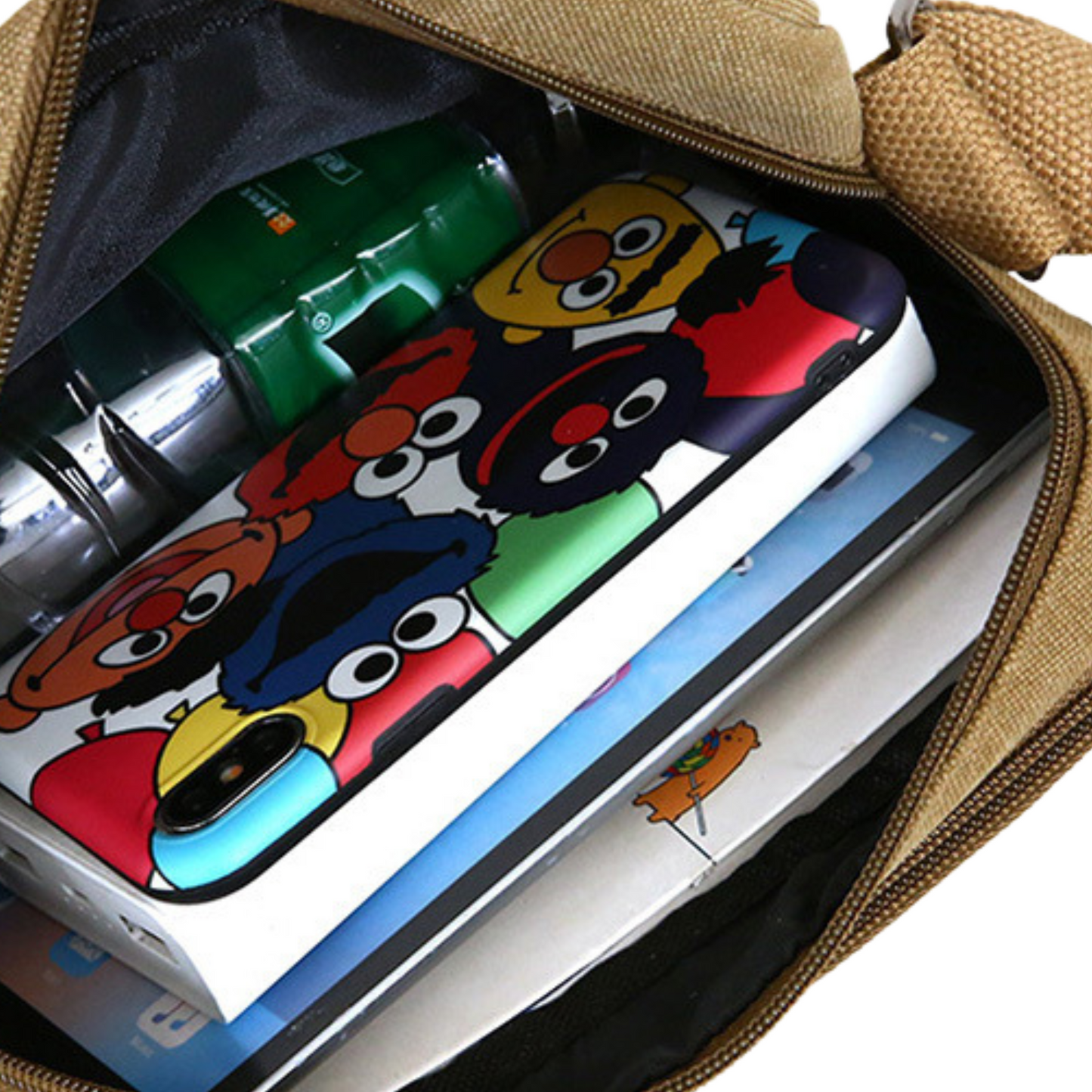 Inside view of a small canvas satchel showing organized items, including a phone and notebook with colorful characters.