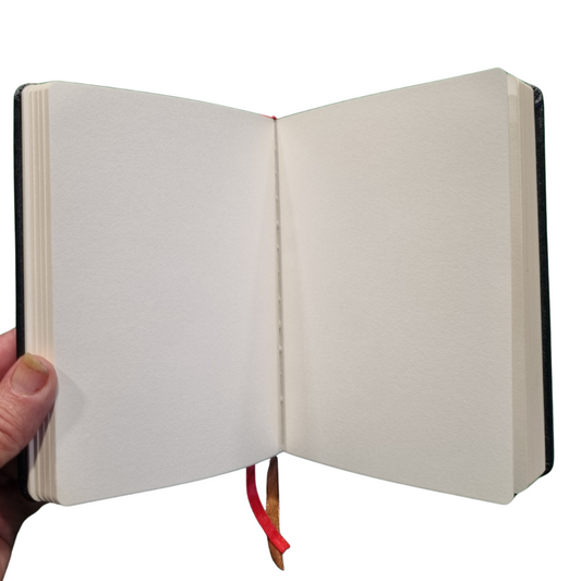 Open view of blank pages inside a black genuine leather travel journal, perfect for writing and sketches.